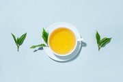 green-tea-brewed-cup-with-tea-leaves-blue-pastel-background-top-view_1220-5336.jpeg
