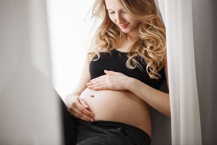 close-up-detail-young-blonde-pregnant-mother-black-outfit-sitting-window-sill-bedroom-touching-looking-belly-with-happy-expression.jpg