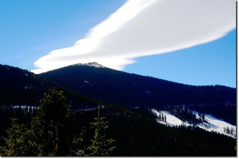 Chief Mountain&apos;s summit barely pokes out above the dense pine forest, taken from the Squaw Pass