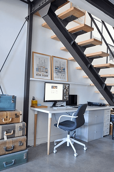 a small contemporary under the stairs home office with a desk with storage, a ledge and vintage suitcases for storage - Shelterness.png