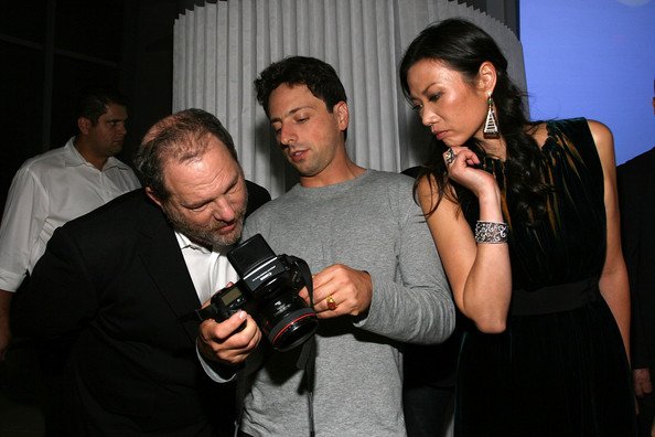 Harvey Weinstein reviews Sergey Brins photography as Wendi Deng looks on during the 23 and Me Spit party at the IAC Building on September 9, 2008 in New York City..bmp