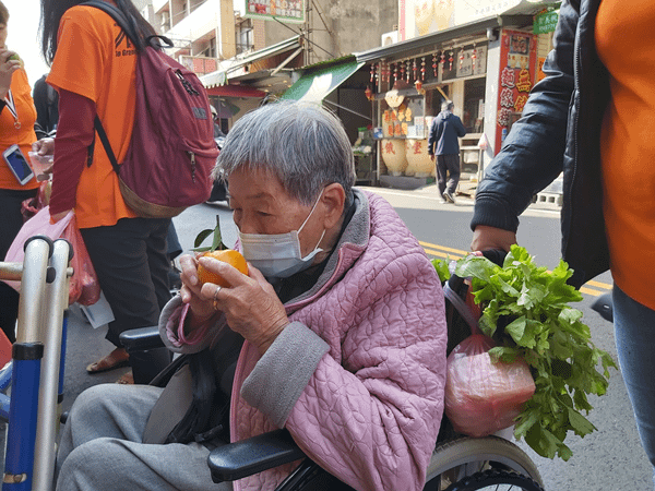 84歲陳阿嬤仔細聞橘子的香氣，購買年節需要的水果.png
