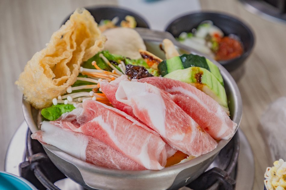 裝滿配料的麻辣牛奶鍋，包含金針菇、青菜與炸豆皮
