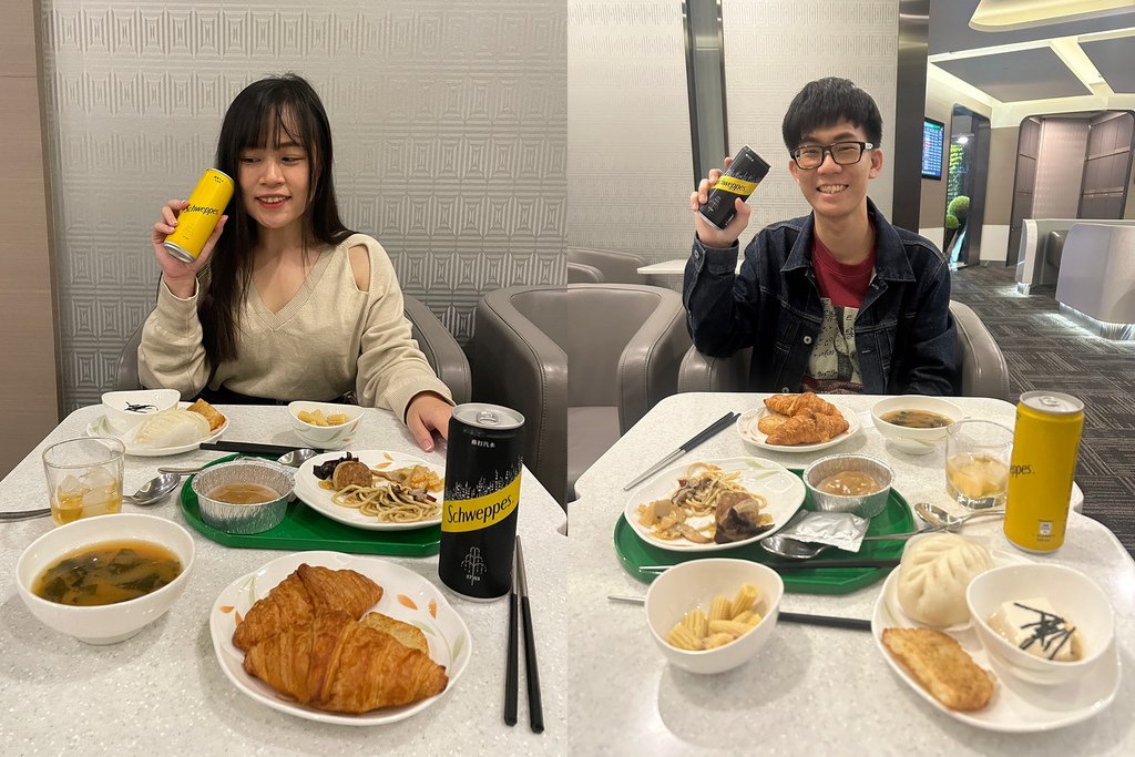 一男一女手拿飲料在貴賓室用餐，桌上擺滿食物.jpg