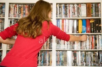 a-girl-choosing-a-dvd-from-a-large-collection-of-dvds-uk-B7JN6R (1)