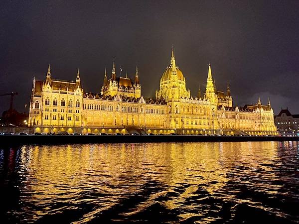 布達佩斯國會大廈的夜景，金色燈光映照在多瑙河上，充滿壯麗氣勢。